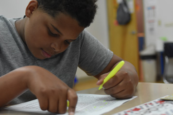 A young boy looks down at his assignment in his special education classroom.