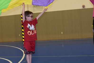 A boy plays with other students in the gym of his special needs school.