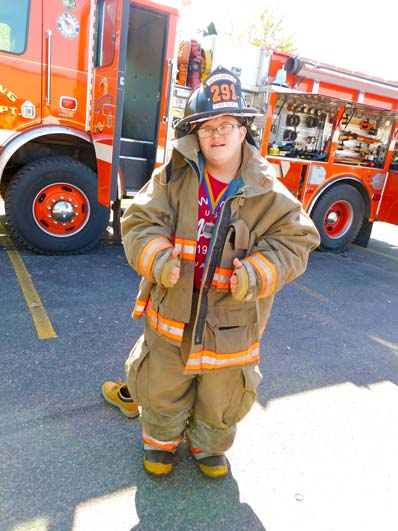 A special education student poses in fire fighters' gear during a field trip