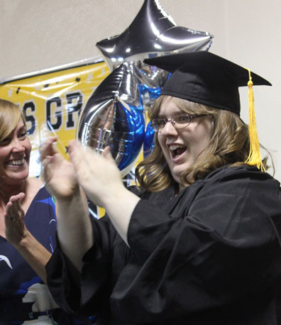 A special education student cheers in a cap and grown at a graduation ceremony