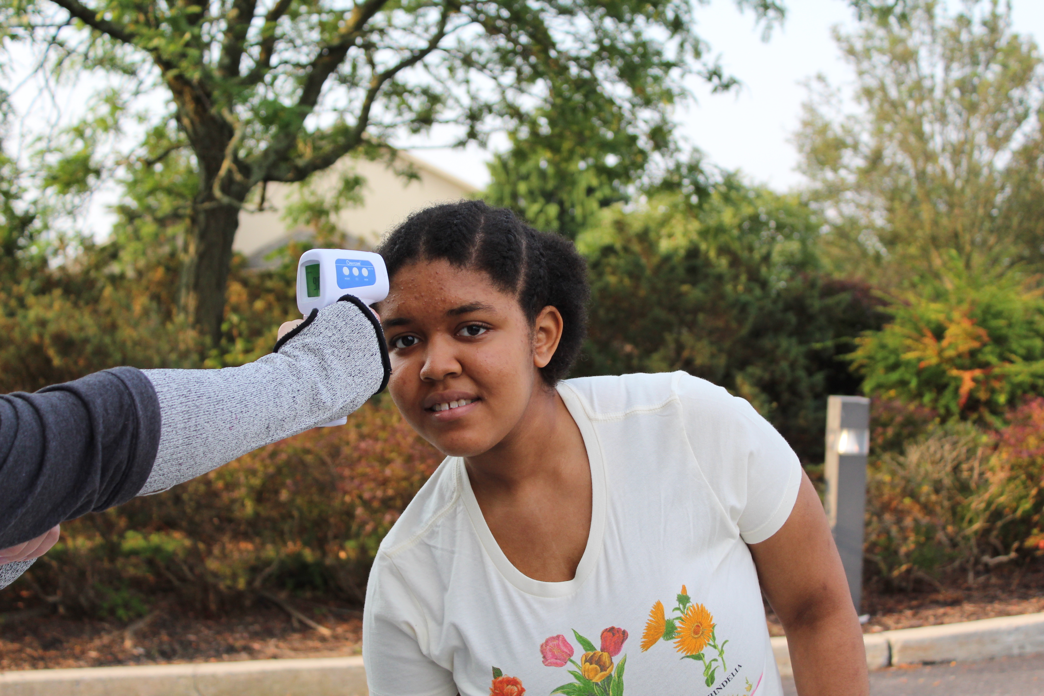 Student leans forward for a temperature check before school. 