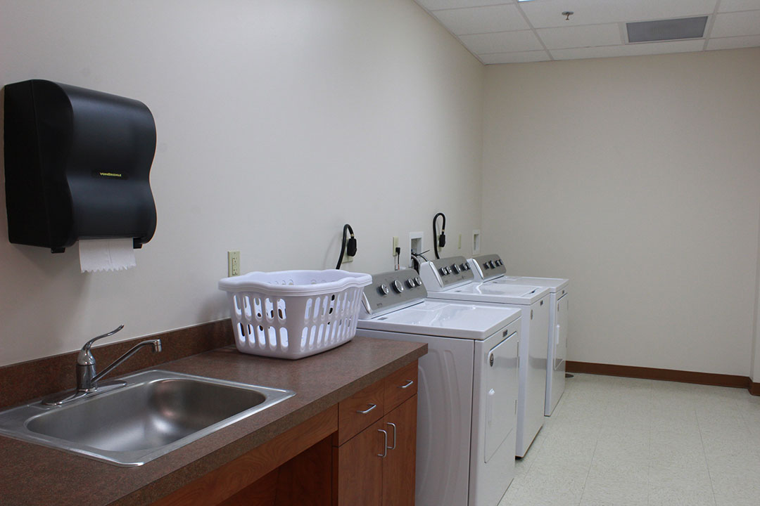 Life Skills Area with utility sink, laundry basket, washer and dryer. 