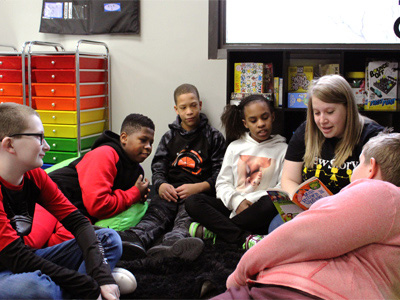A special education teacher reads to a large group of students in her classroom.