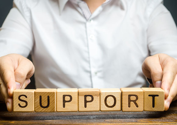 Blocks spell out the word “support” as a man sits behind them