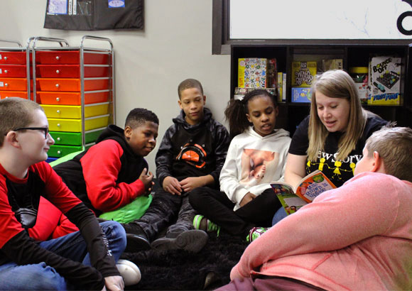A special education teacher reads to a large group of students in her classroom.