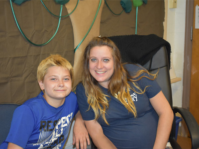 A special education student and teacher smile together in their classroom.