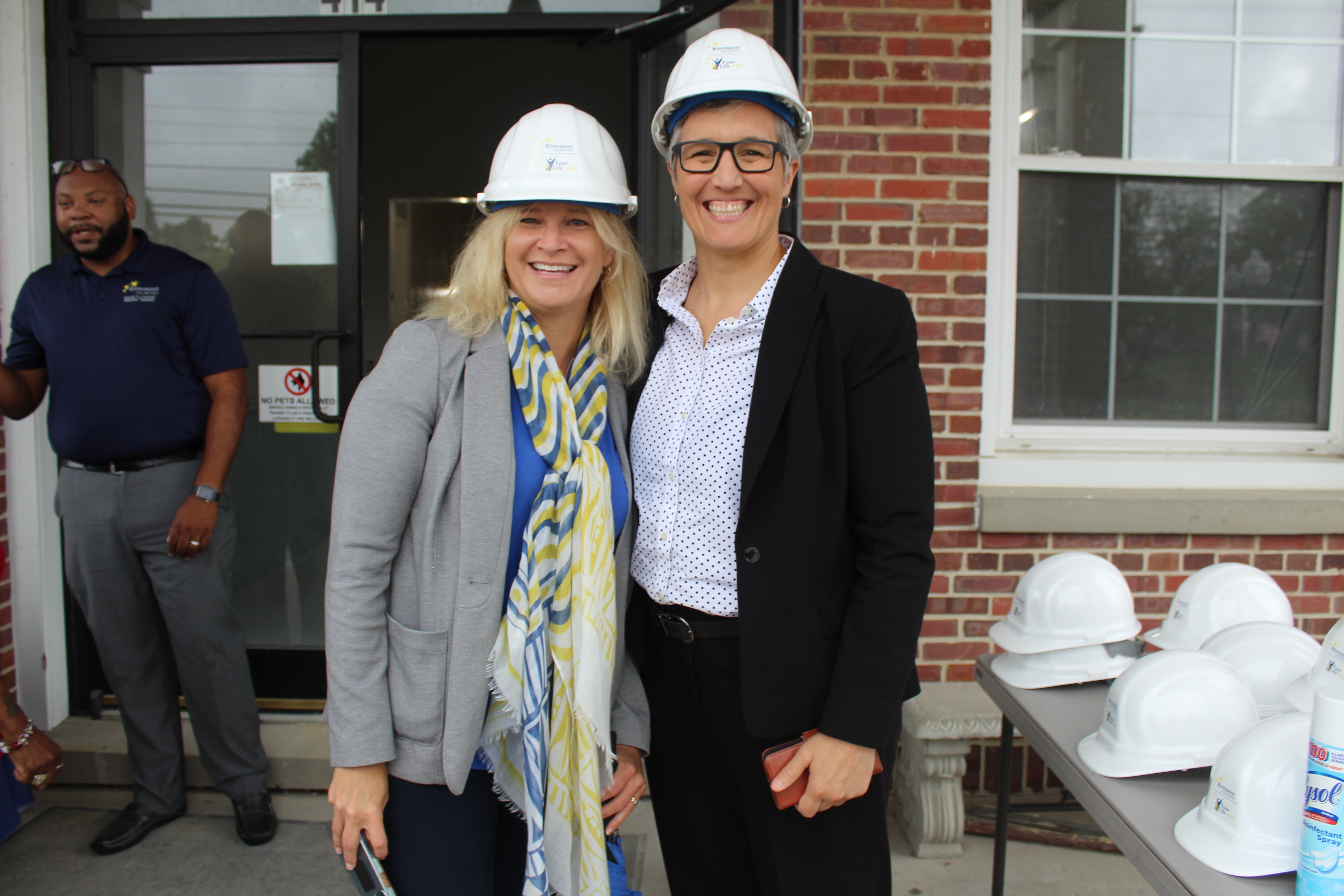 two women posing with hard hats